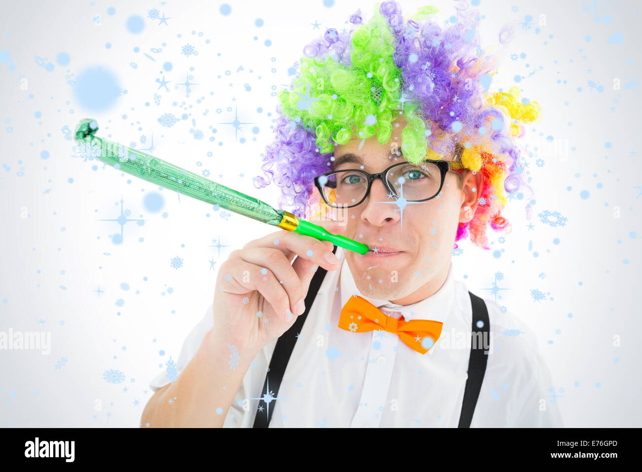 Composite image of geeky hipster wearing a rainbow wig blowing party horn Stock Photo