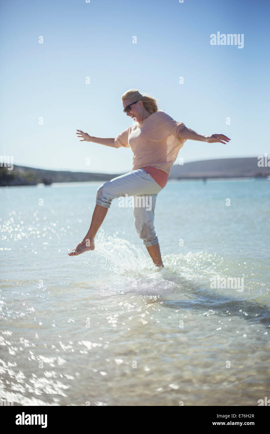 Woman splashing in water on beach Stock Photo