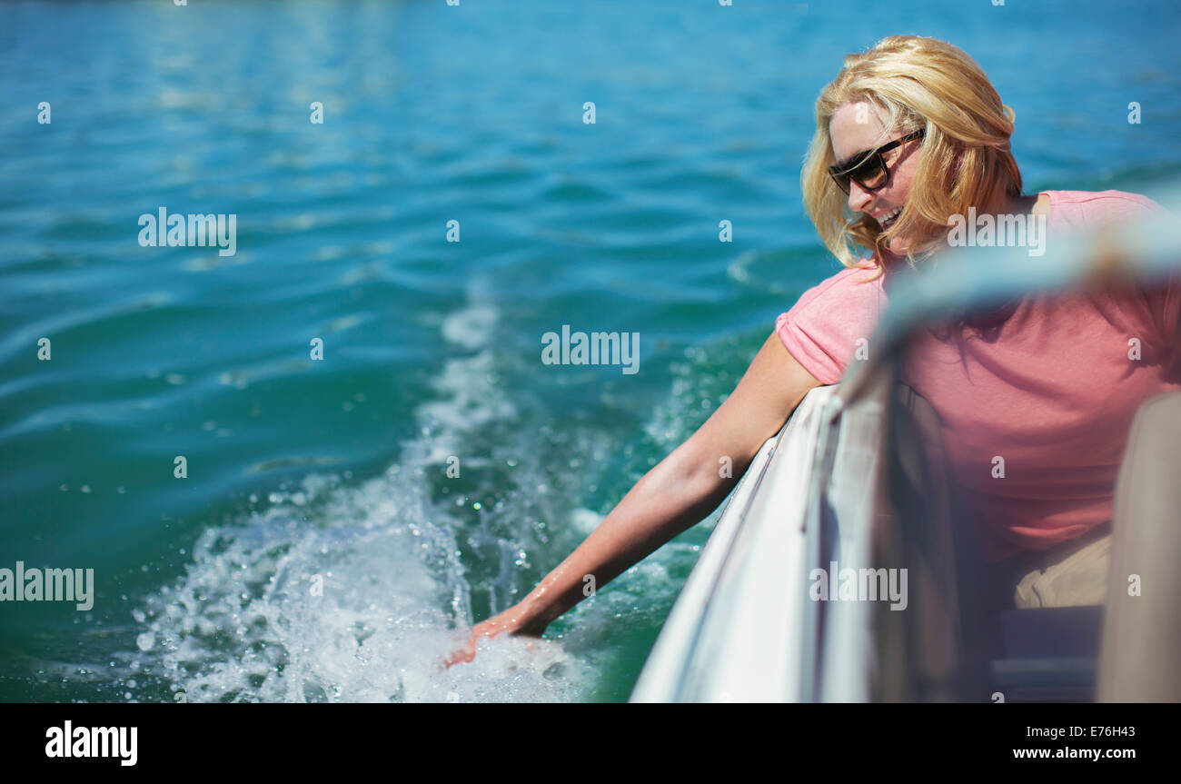 Older woman trailing hand in water from boat Stock Photo