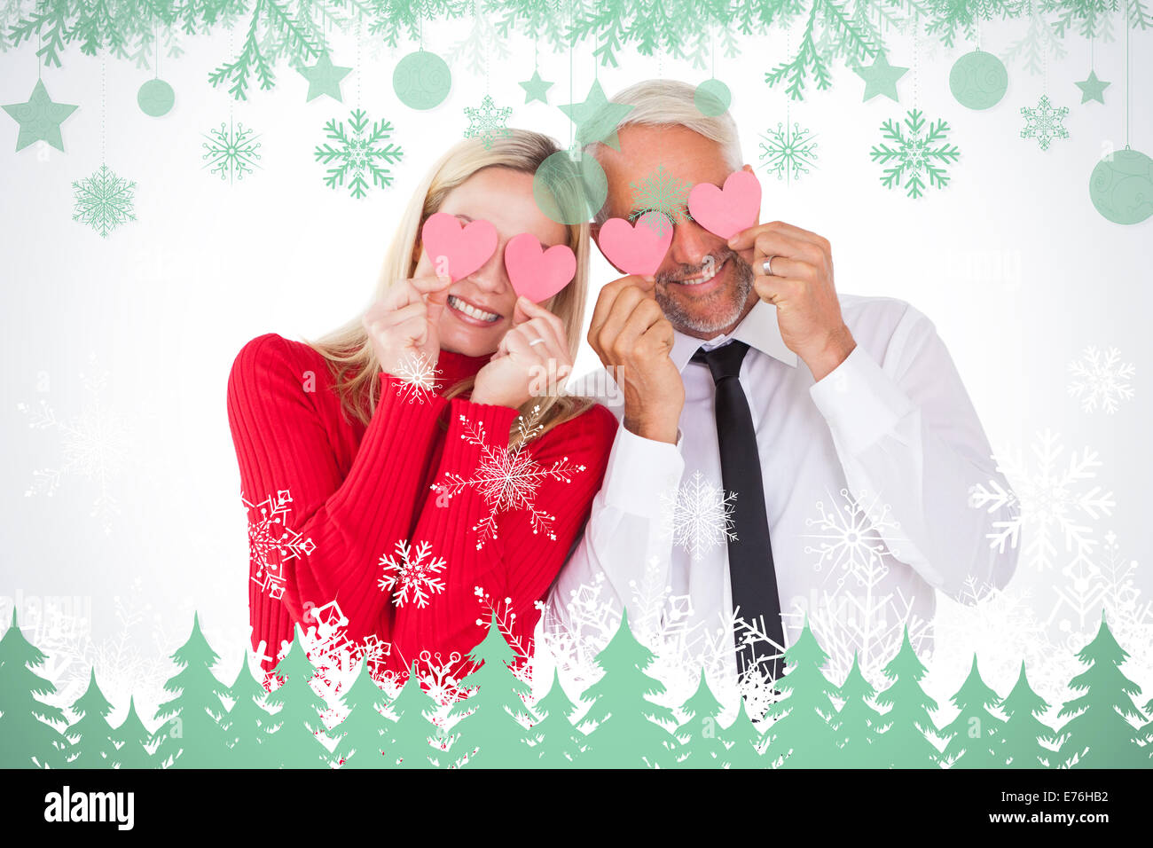 Composite image of silly couple holding hearts over their eyes Stock Photo