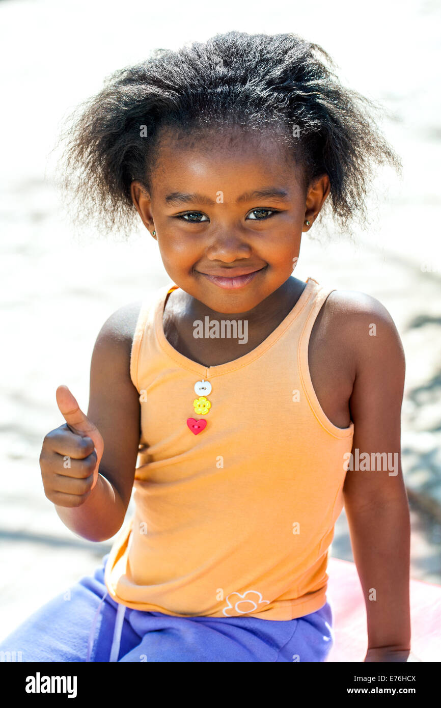 Outdoor portrait of cute African girl doing thumbs up sign. Stock Photo