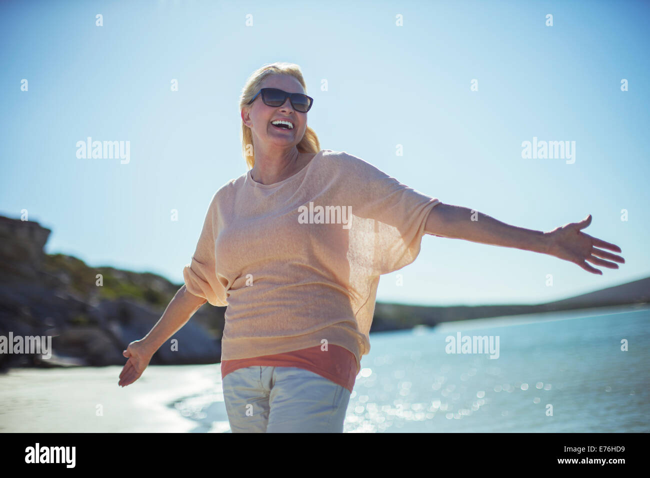 Older woman smiling in sun on beach Stock Photo