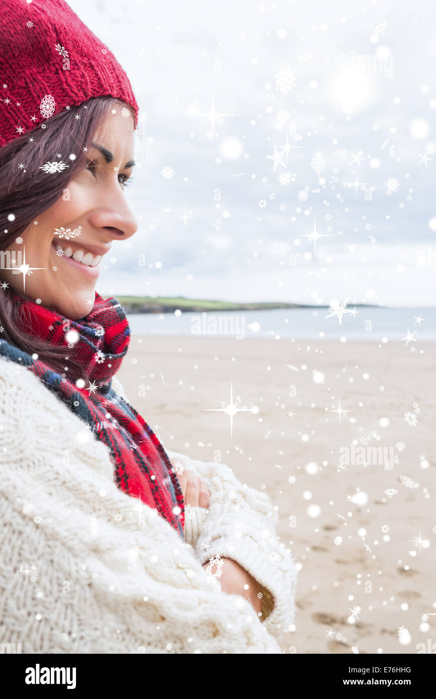 Composite image of woman in knitted hat and pullover smiling at beach Stock Photo