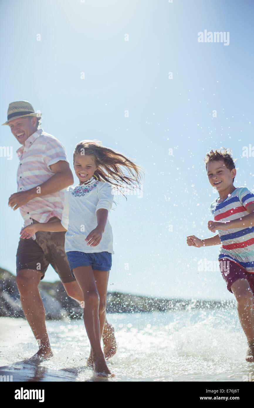 Family running in water on beach Stock Photo