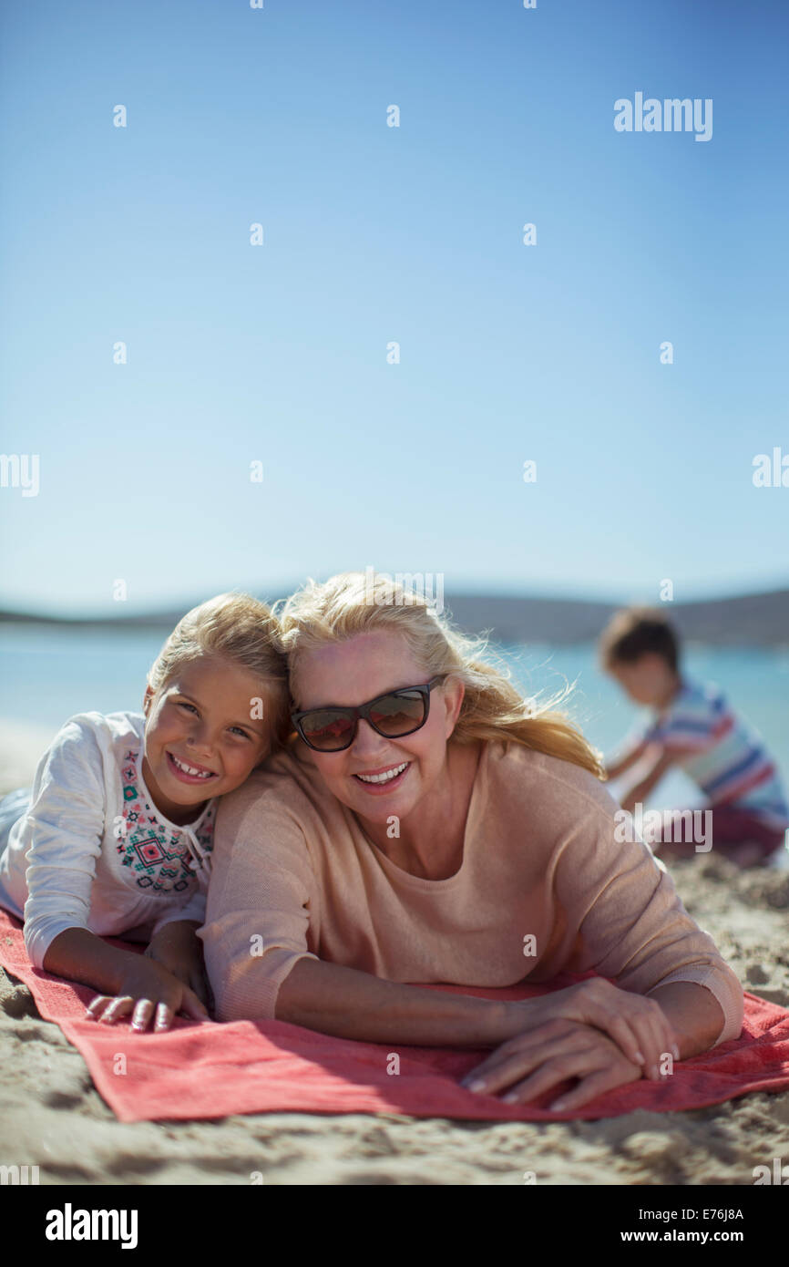 Grandmother and granddaughter laying on beach towel together Stock Photo