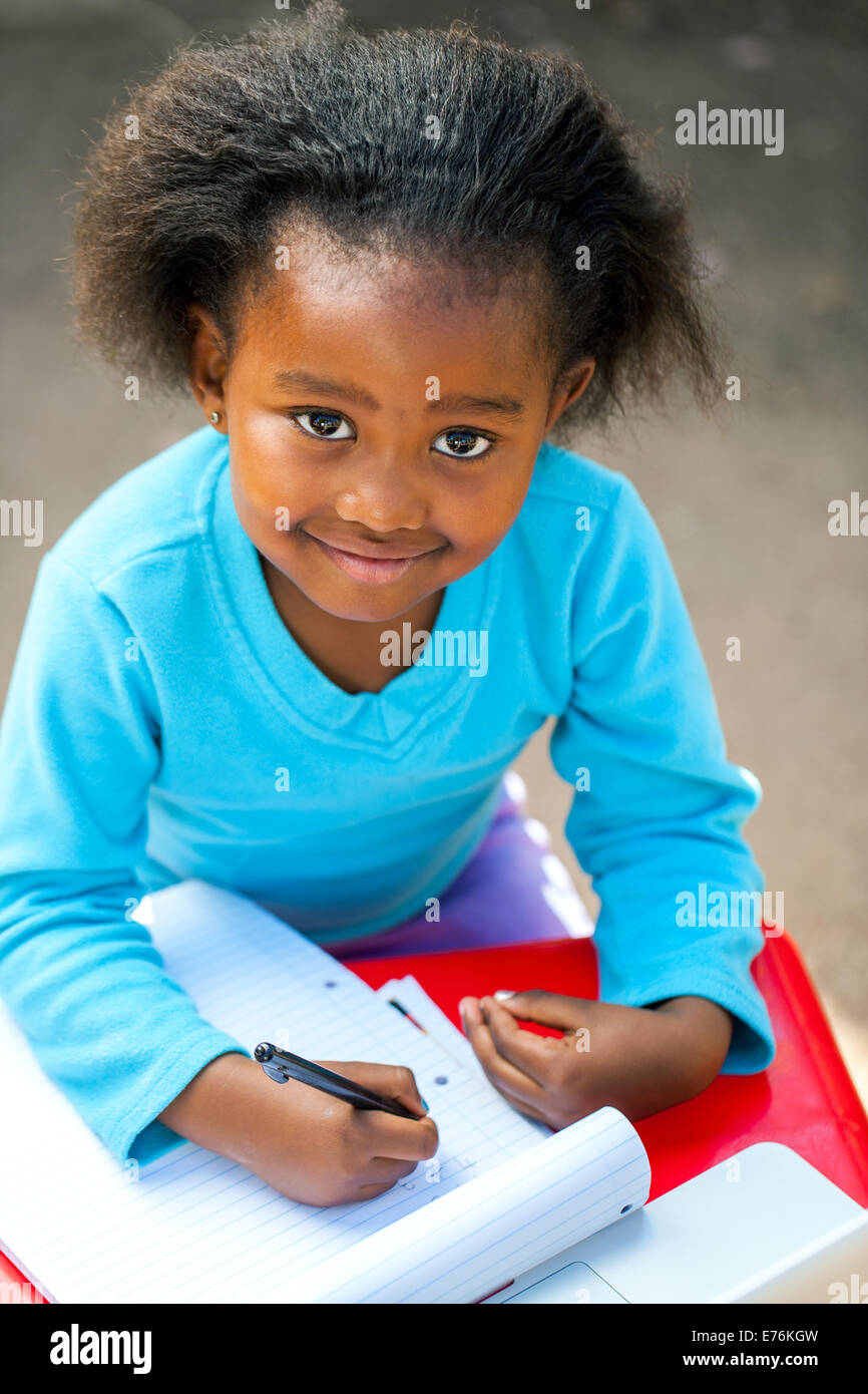 Portrait of small African kid writing in notebook at desk Stock Photo