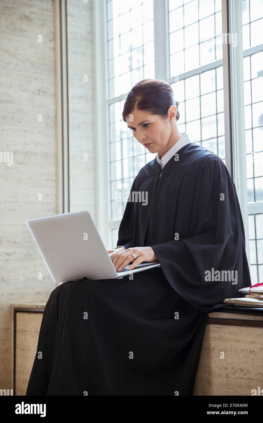 Judge sitting on bench using laptop in courthouse Stock Photo