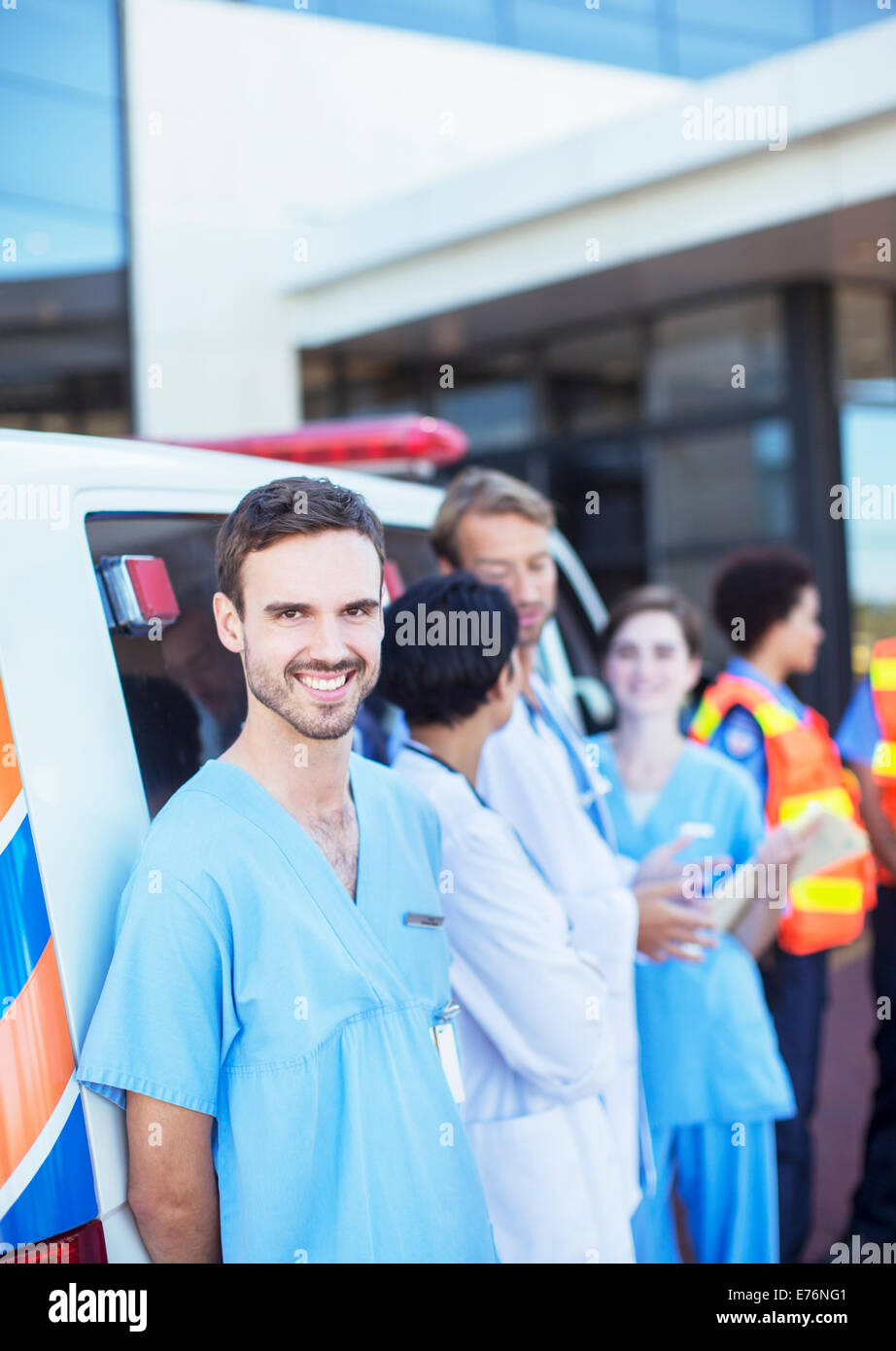 Nurse smiling by ambulance in hospital parking lot Stock Photo