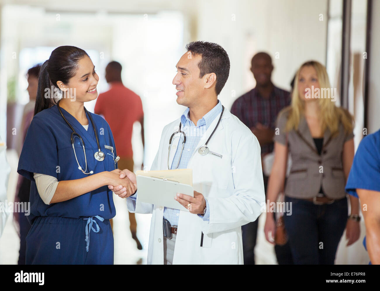 Doctor and nurse shaking hands in hospital hallway Stock Photo