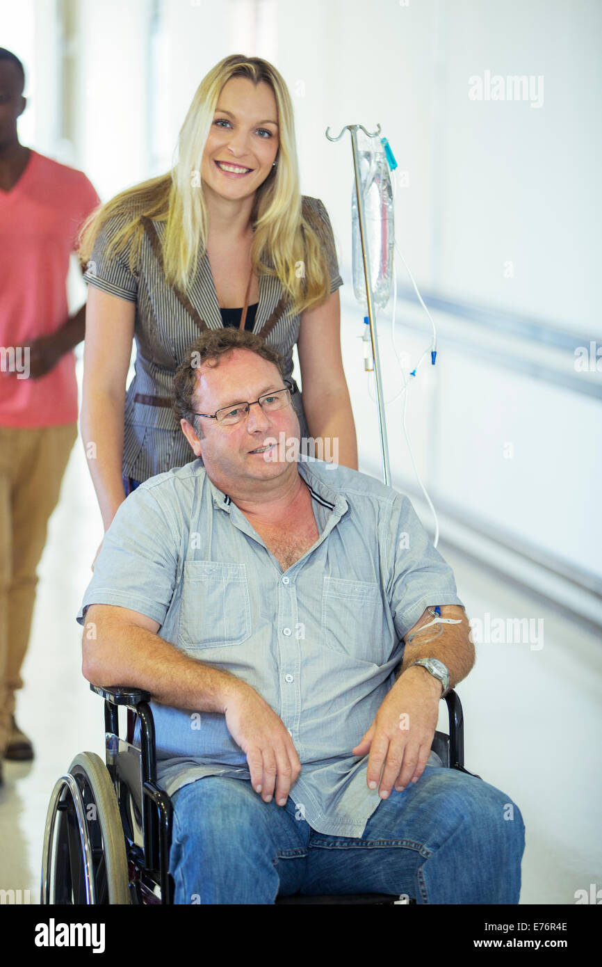 Woman wheeling father in hospital hallway Stock Photo