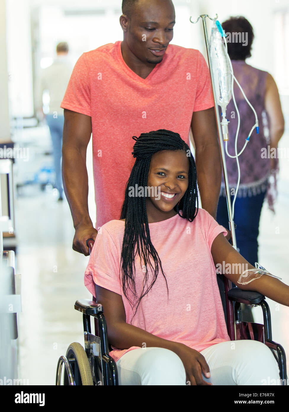 Man wheeling girlfriend in hospital hallway Stock Photo