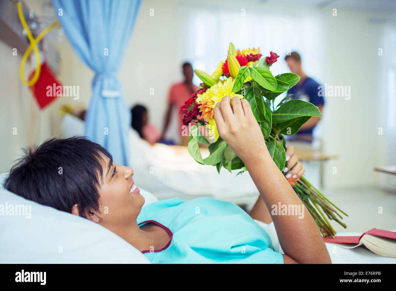 Patient admiring bouquet of flowers in hospital room Stock Photo