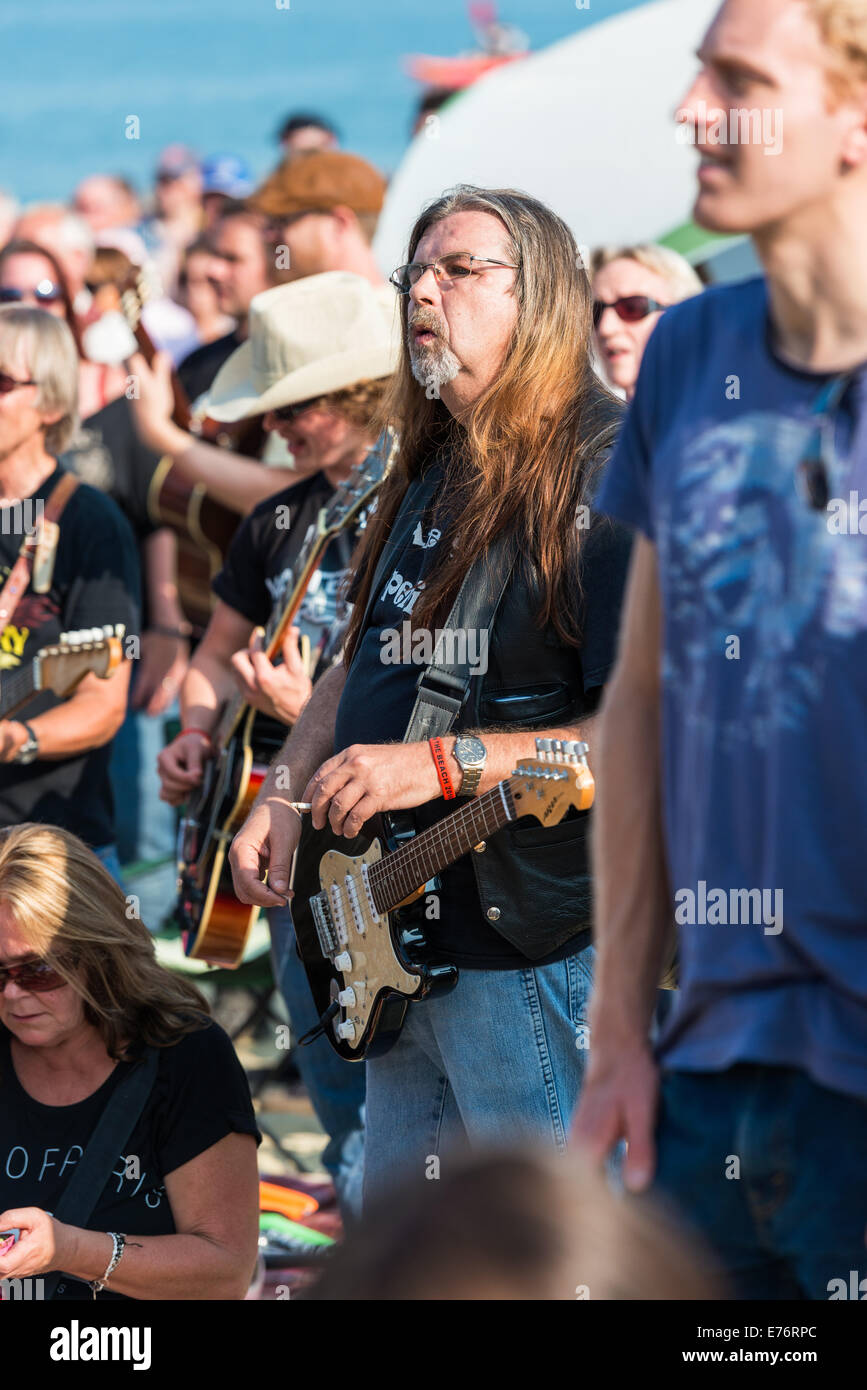 Lyme Regis, Dorset, England. Some  guitarists at the Guitars on the Beach event plays along with Rockin' all over the World Stock Photo