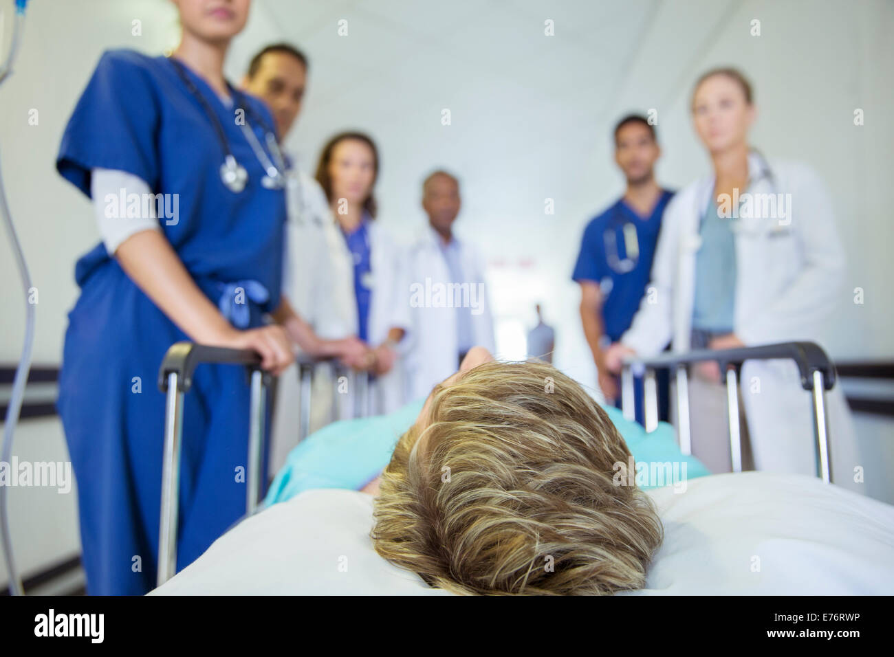 Doctors and nurses wheeling patient in hospital hallway Stock Photo