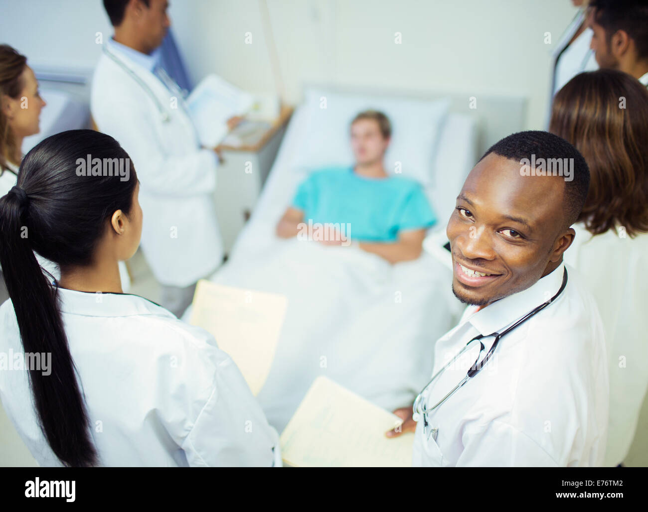 Doctor standing with residents in hospital room Stock Photo