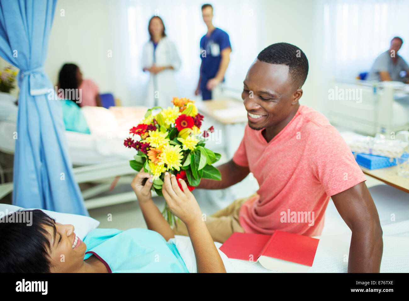 Man giving girlfriend bouquet of flowers in hospital Stock Photo