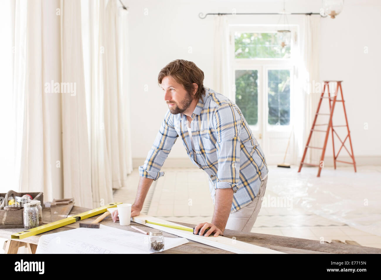 Man overlooking construction table in living space Stock Photo