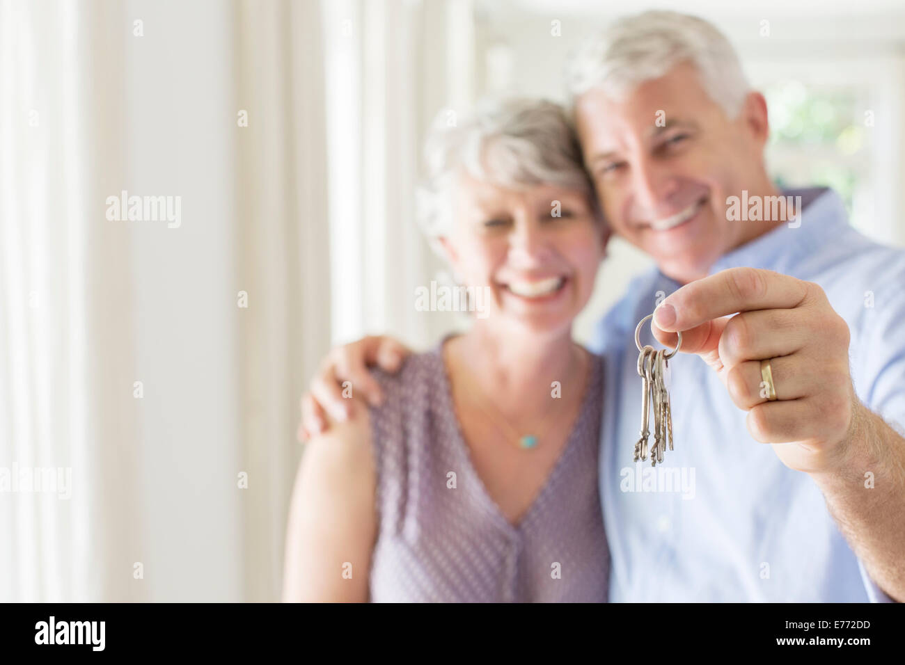 Older man holding keys with wife Stock Photo