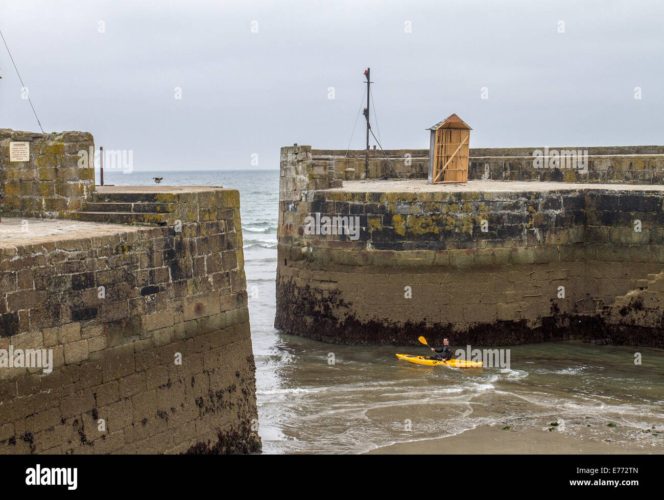 A canoeist paddling out of the harbour of Charlestown, a village and port on the south coast of Cornwall, England UK Stock Photo