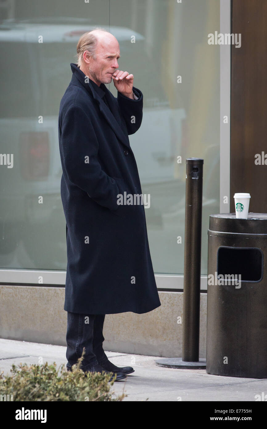 An unshaven Ed Harris lights up a cigarette while taking a coffee break, resting his cup on a