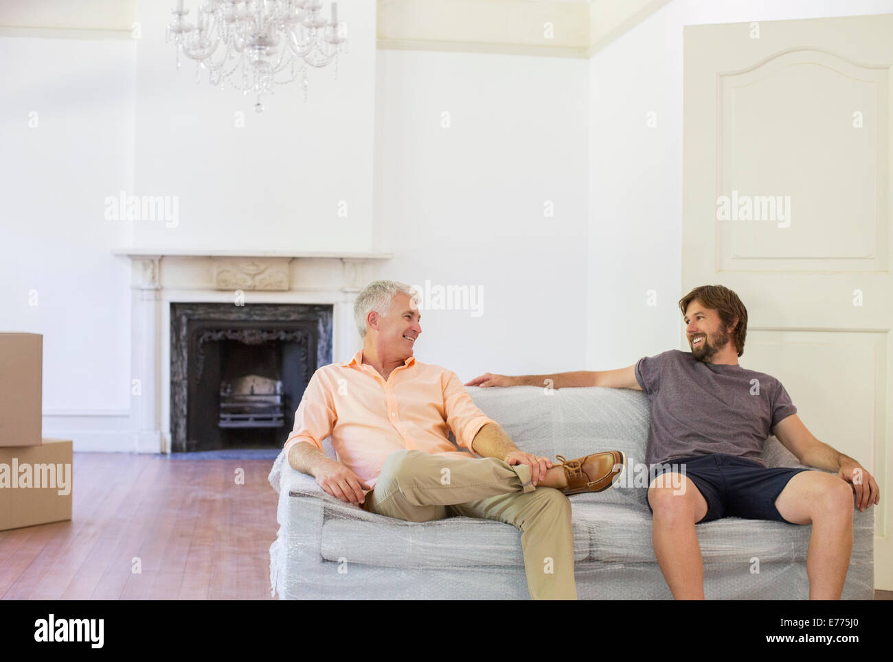 Father and son sitting on couch in living space Stock Photo