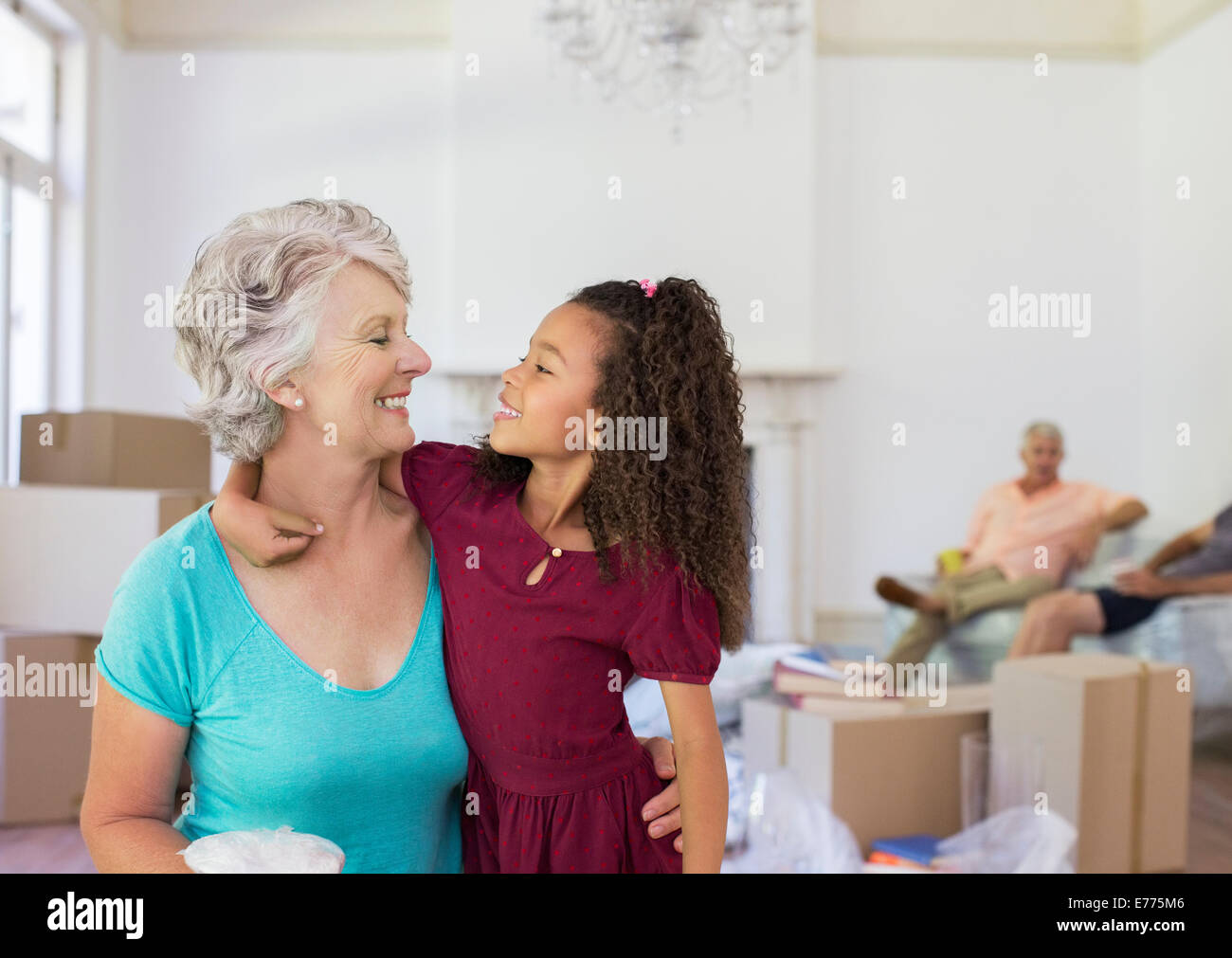 Grandmother and granddaughter hugging in living space Stock Photo