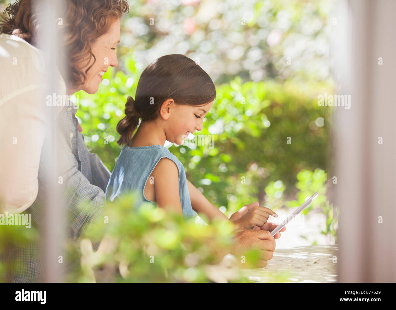 Granddaughter playing on digital tablet with granddaughter Stock Photo