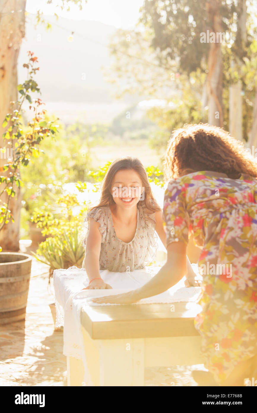 Mother and daughter laying table cloth on table Stock Photo