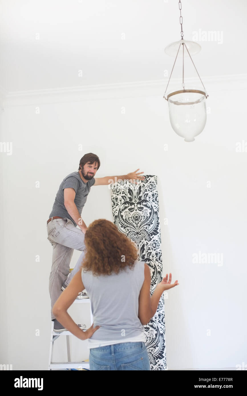 Couple deciding on wallpaper on wall Stock Photo