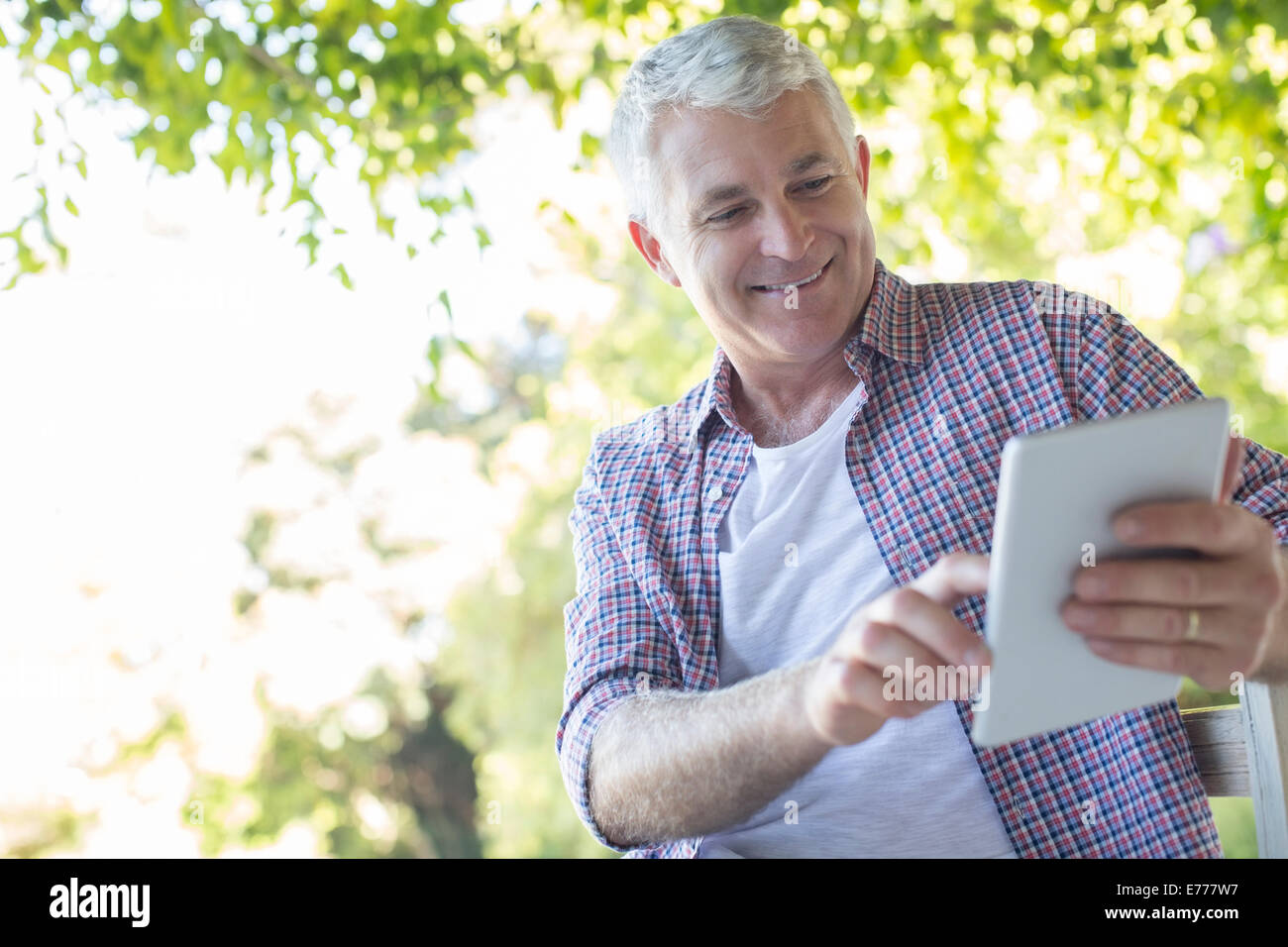 Older man using digital tablet outdoors Stock Photo