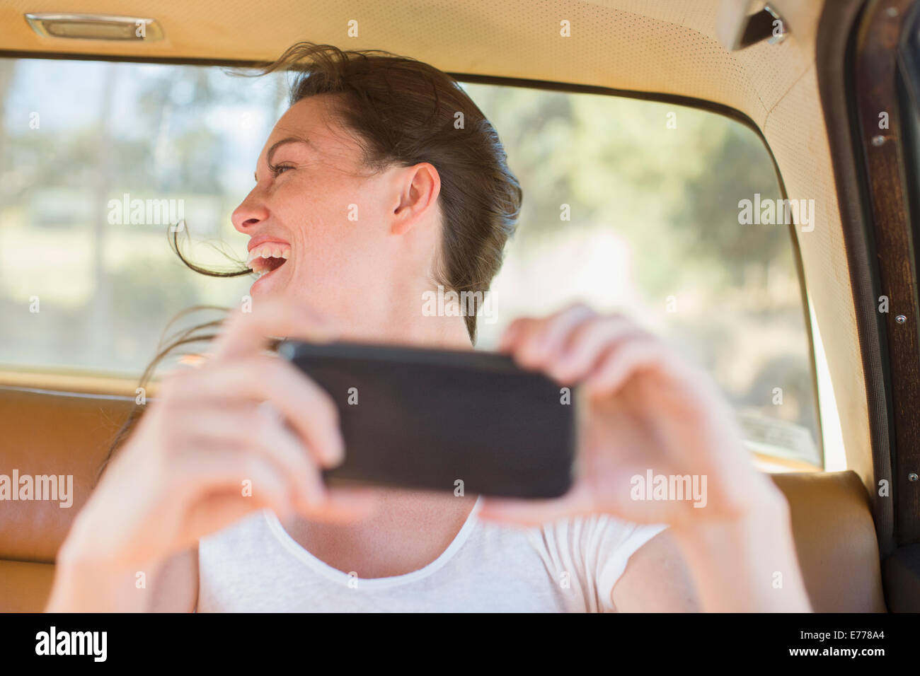 Woman in car backseat taking picture with cell phone Stock Photo