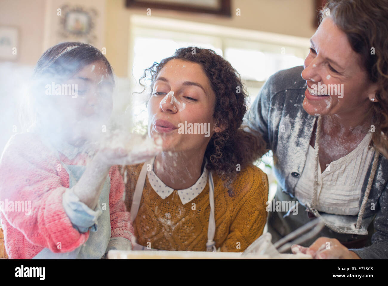 Three generations of women playing with flour Stock Photo