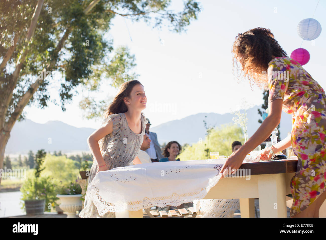 Mother and daughter laying table cloth on table Stock Photo