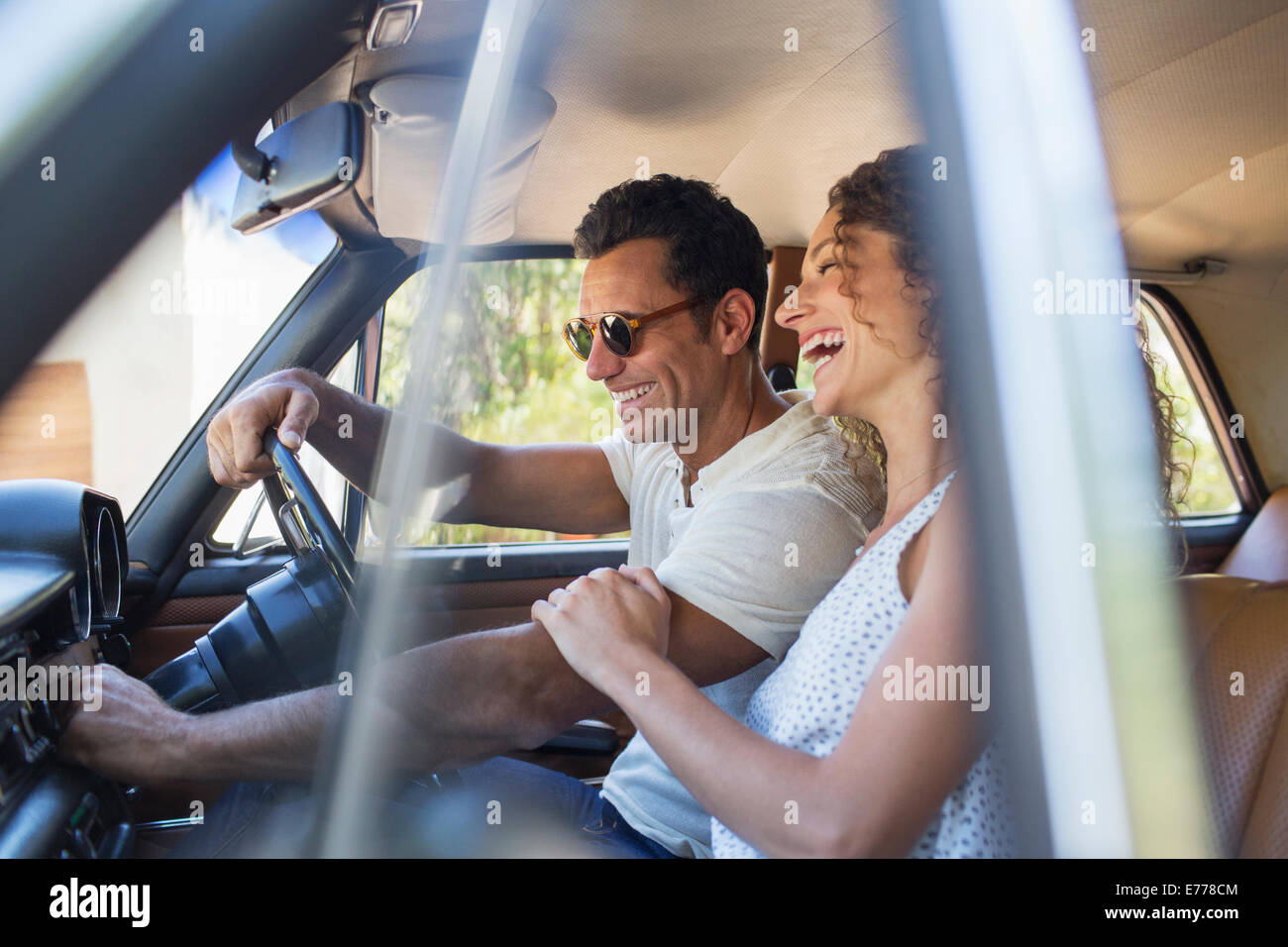 Couple riding in car on sunny day Stock Photo