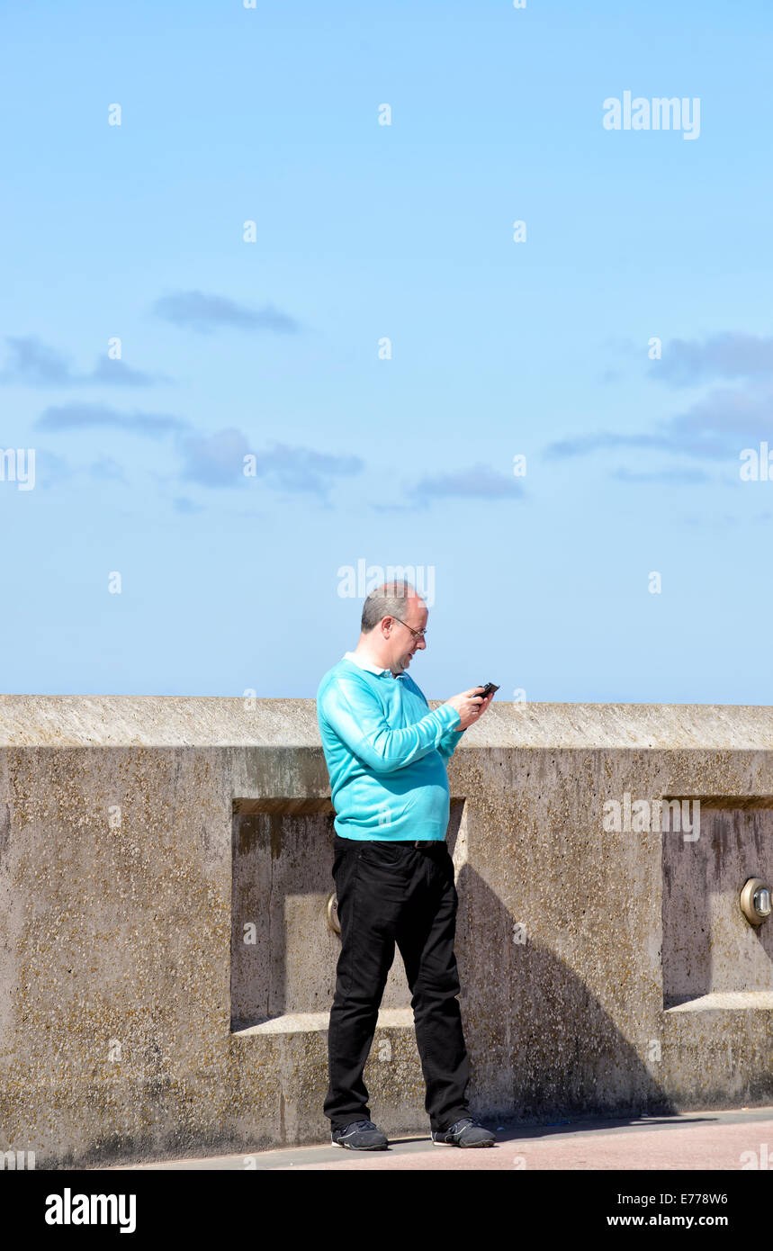 Man in bright pullover, using his mobile phone Stock Photo