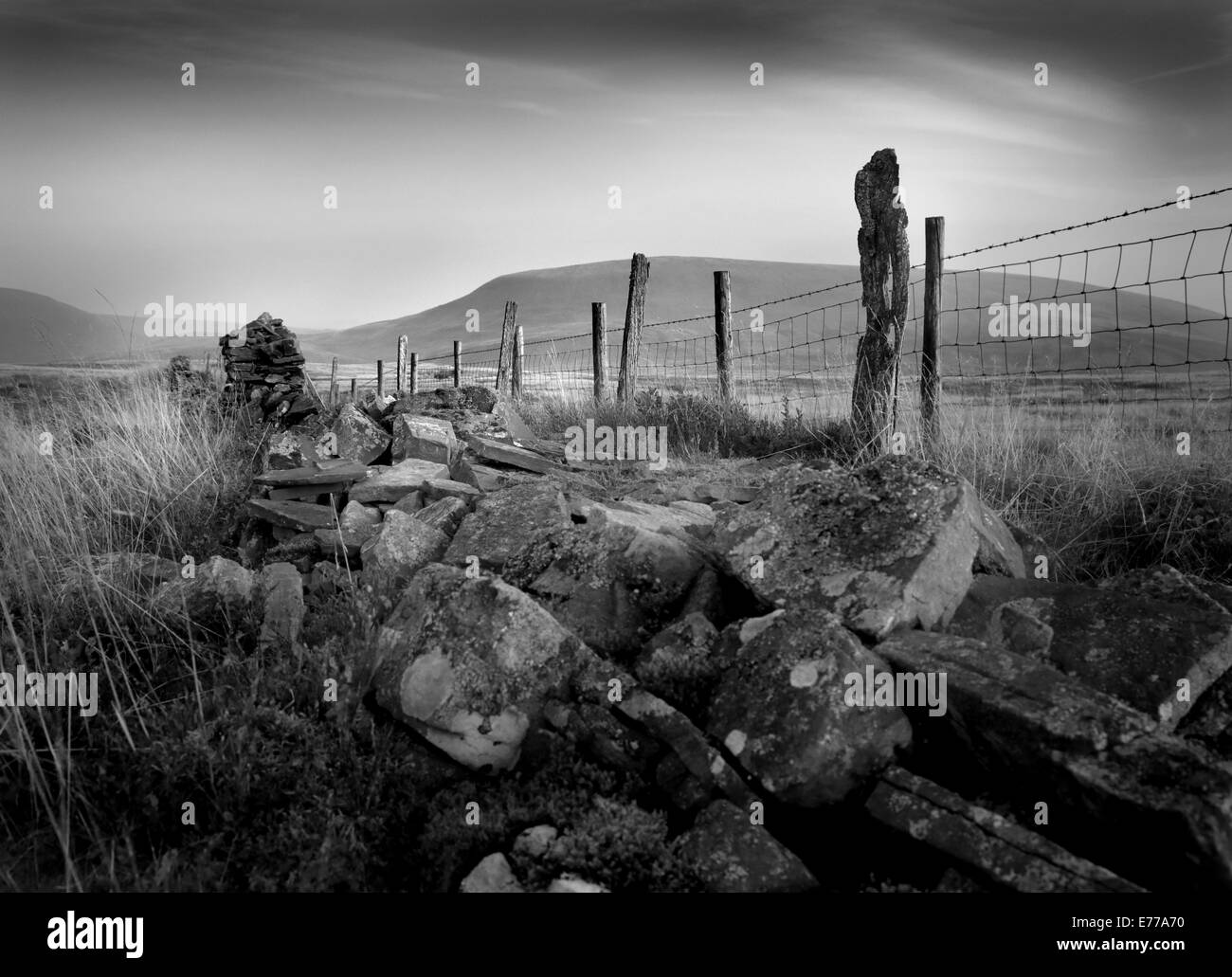 Upland landscape in Brecon Beacons National Park, with old fenceline, moody atmosphere, rocks and mountains in late evening Stock Photo