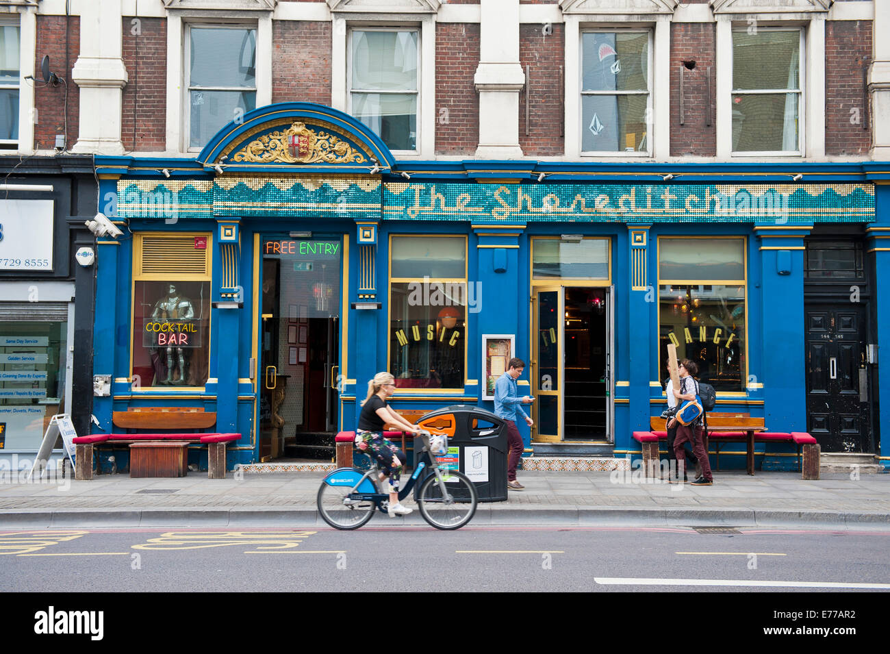 The Shoreditch, bar, restaurant and music venue in the East End of London, with a girl on a 'boris bike' driving past. Stock Photo