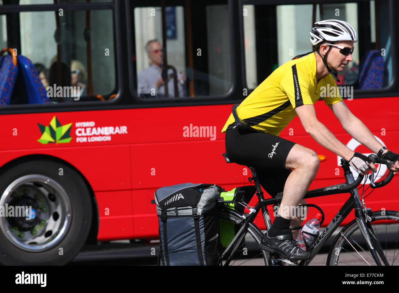 A cyclist riding alongside a red London bus Stock Photo - Alamy