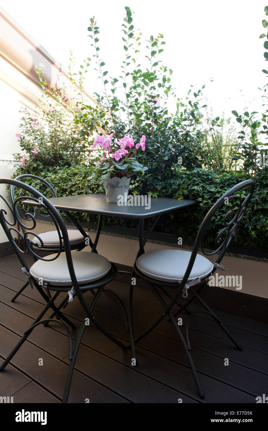 Small balcony table with chairs and flower pot Stock Photo
