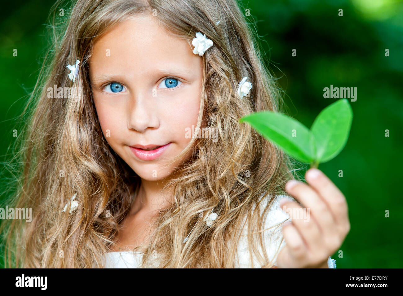 Close up face portrait of attractive girl holding green leaf outdoors ...