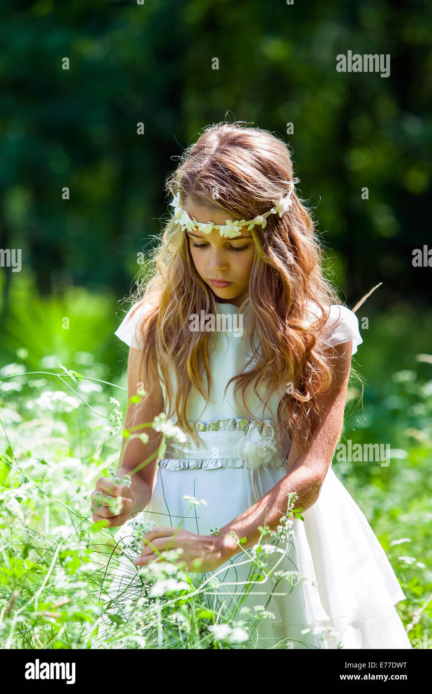 Close up portrait of cute girl picking flowers in field. Stock Photo