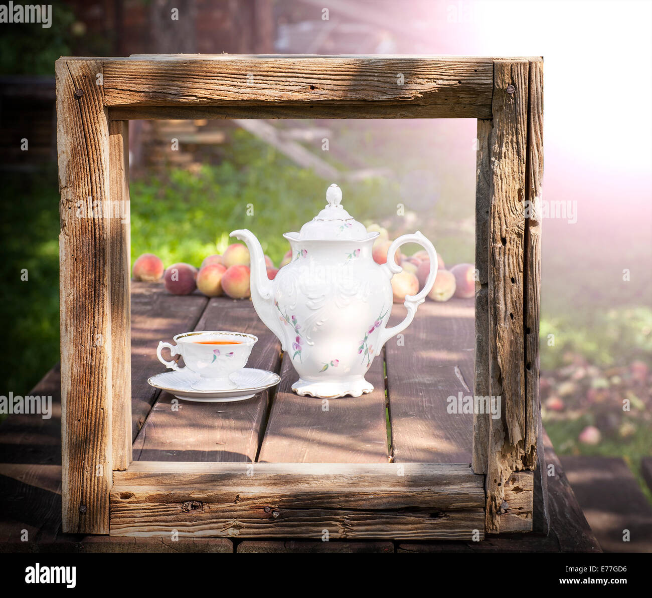 Vintage picture of tea set in garden in wooden frame. Stock Photo