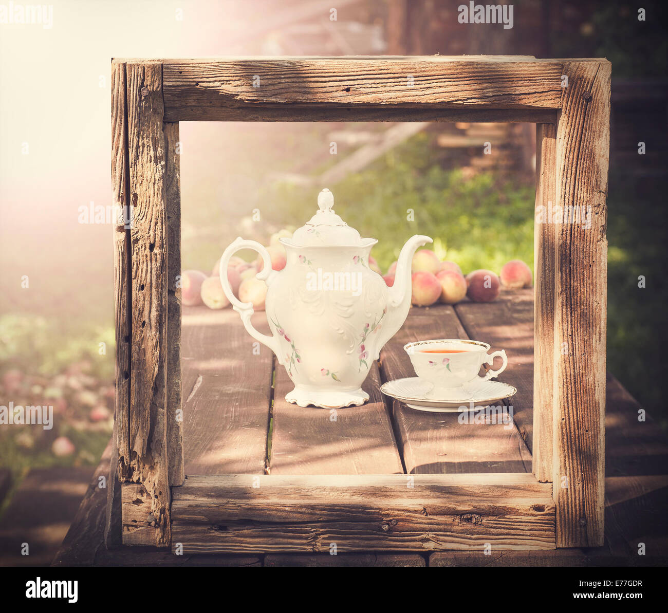 Vintage picture of tea set in garden in wooden frame. Stock Photo