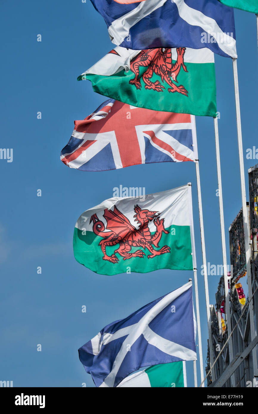 A selection of the United kingdom's home nations flags flying together atop flagpoles against a blue sky Stock Photo