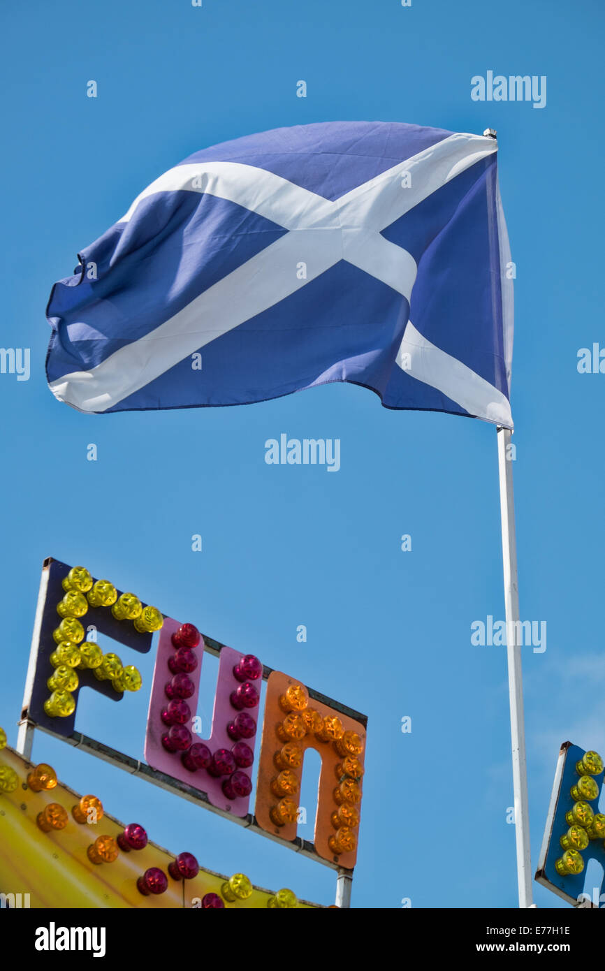 The Saltire, the Scottish national flag flying atop a flagpole above the word fun written in multi coloured  fairground lights Stock Photo