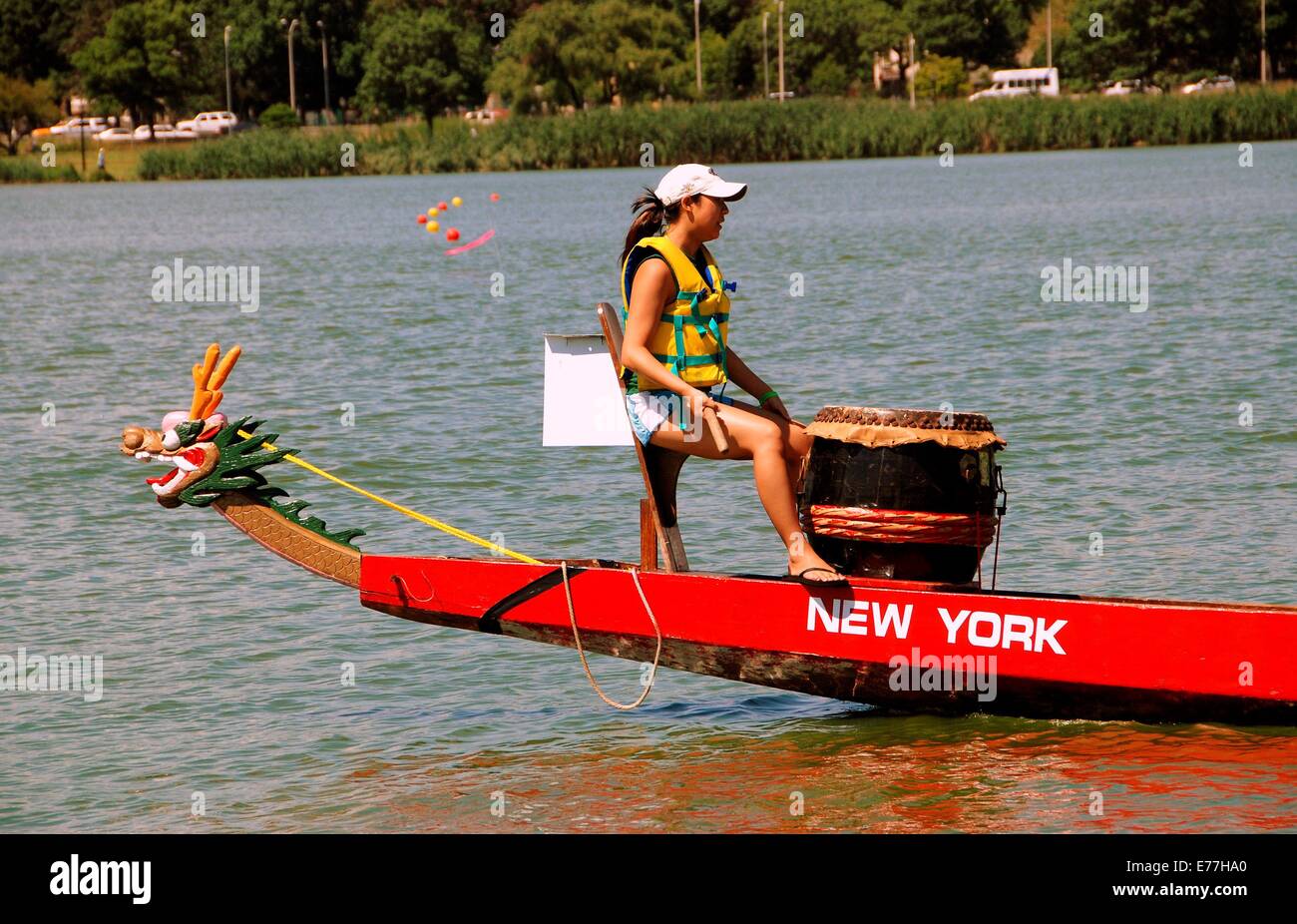 QUEENS, NY:  Woman drummer standin on the bow beating rhythm during the Hong Kong Dragon Boat Races in Flushing Meadows Park Stock Photo