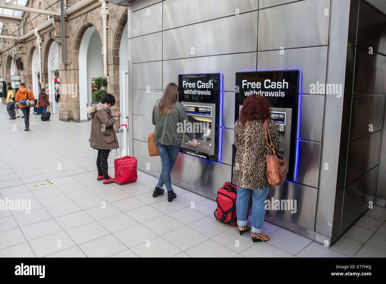 Travelers using free cash withdrawal at ATM automated teller machines in railway station in England UK Stock Photo