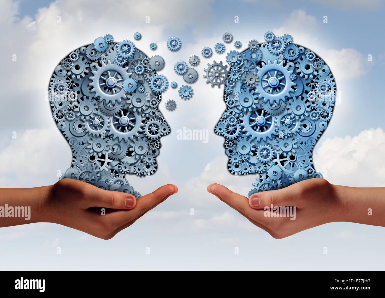 Business technology concept as two hands holding a group of  machine gears shaped as a human head as a symbol and metaphor for the transfer of industry information or corporate training. Stock Photo