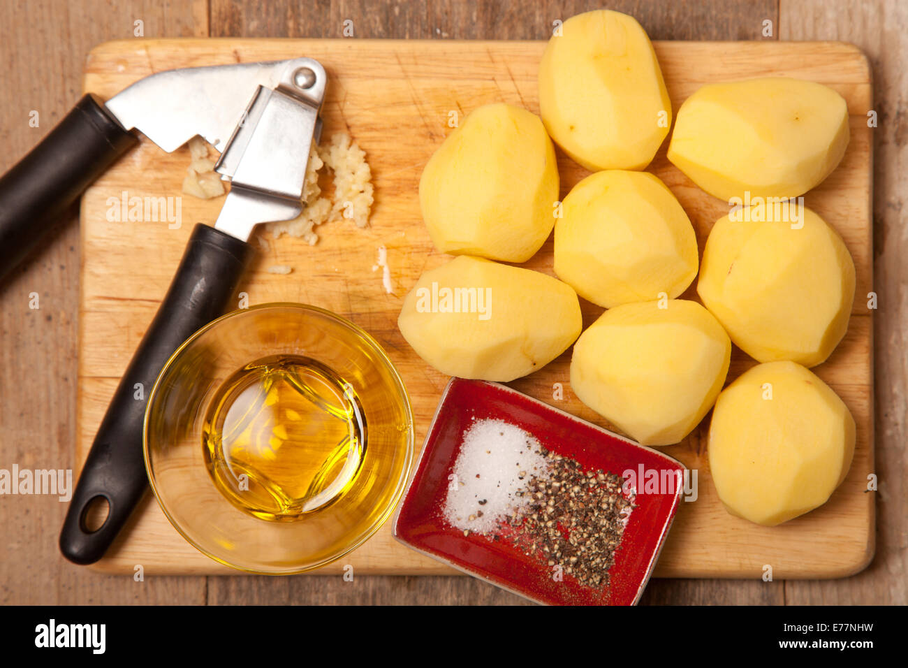 peeled potatoes on chopping board with crushed garlic olive oil Stock