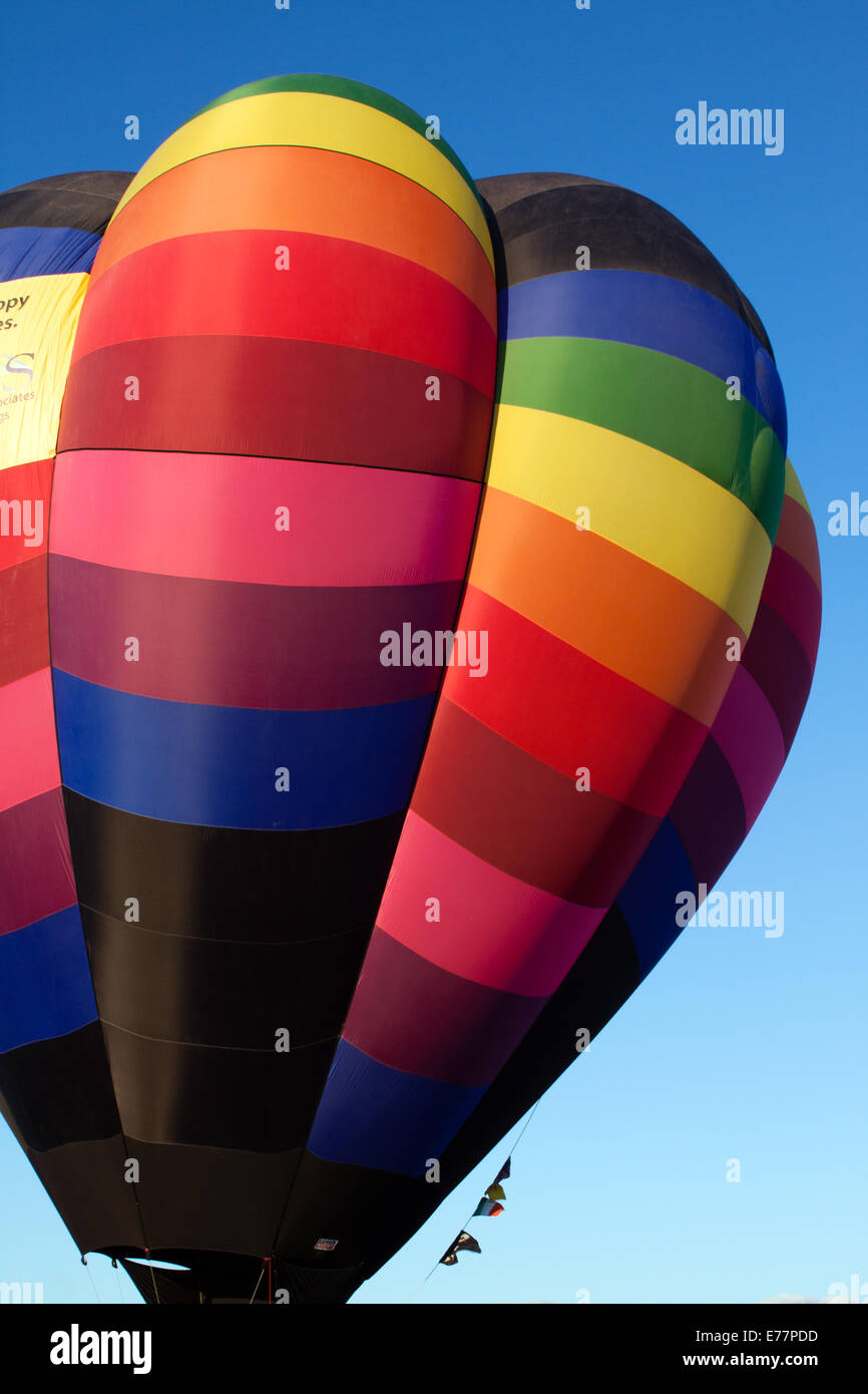Rainbow-colored hot air balloon against a blue sky Stock Photo